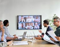Diverse executive sitting around a table with other participants on screen