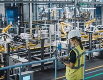 Female manufacturing employee using laptop on plant floor