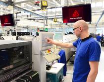 Manufacturing employee working in plant with system hacked sign overhead