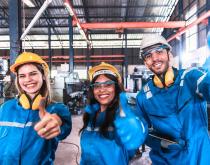 Diverse factory employees in PPE smiling for camera