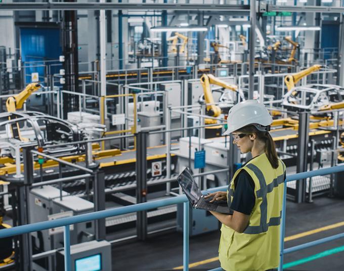 Female manufacturing employee using laptop on plant floor