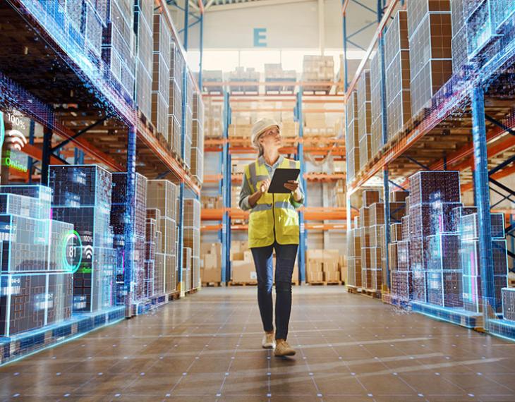 Woman walking through warehouse using technology